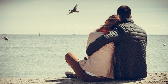 couple devant une plage s'enlacant